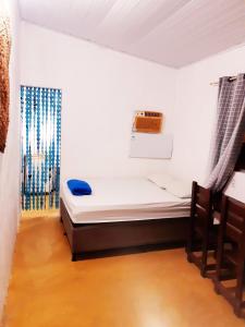 een kleine kamer met een bed en een klok aan de muur bij Casinha Guiné in Morro de São Paulo