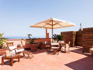 eine Terrasse mit einem Sonnenschirm, Tischen und Stühlen in der Unterkunft San Domenico Apartment in Taormina