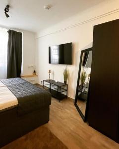 a bedroom with a bed and a flat screen tv at City Apartments Trier Suite 5 in Trier +2 photos