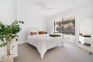 a white bedroom with a white bed and a window at Rye Beach House - Sunset Views in Rye