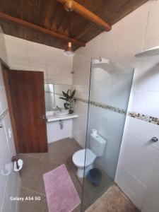 een badkamer met toilet en glazen douche bij Alma Surf House in Boicucanga