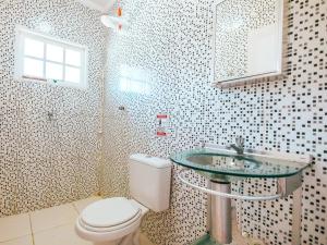 Un baño con inodoro y lavabo de cristal. en Pousada Sol Nascente, en Ubatuba
