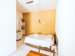 Un dormitorio con una cama blanca y una pared amarilla. en Pousada Sol Nascente, en Ubatuba