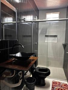 a bathroom with a black toilet and a shower at Lessa imob in Salinópolis +9 photos