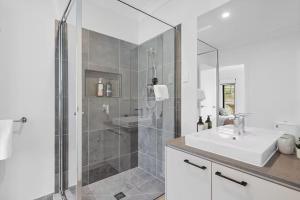 a white bathroom with a shower and a sink at Golf Club Mystic Tides by Ready Set Stay in San Remo +20 photos