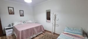 a white bedroom with a bed and a chair at Casa no centro aproveite o melhor de Foz in Foz do Iguaçu