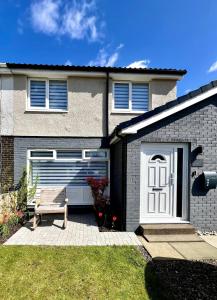 a house with a white door and a bench in the yard at Dunmuir House 4 Bedroom 2 bathroom House & Garden in Denny in Falkirk