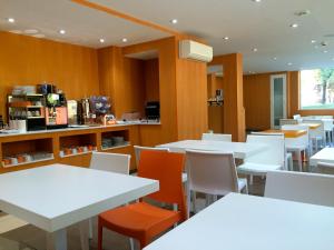 ein Esszimmer mit weißen Tischen und orangefarbenen Stühlen in der Unterkunft Hotel Indiana in Pinto