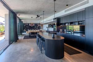 una cocina con armarios negros y un bar con taburetes en Haven House at Hamilton Island, en Hamilton Island