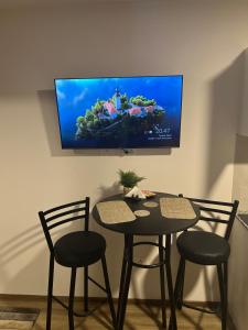 a dining room table with two chairs and a television on the wall at Cómodo y confortable Estudio in Cochabamba