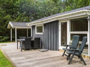 a wooden deck with chairs and a table on it at Holiday home with spacious garden in Løkken
