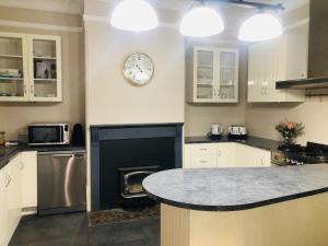 una cucina con camino e orologio sul muro di Belmore Cottage - Historic home in Central South ad Armidale