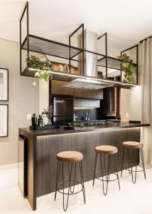 a kitchen with three stools and a counter with a sink at Apto novo e confortável em Canto Grande, Bombinhas in Bombinhas