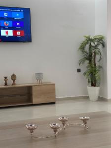 a room with a tv and a table with a plant at Luxury Terrace Apartment in Al Hoceïma