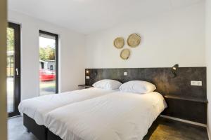 a bedroom with a large bed with a wooden headboard at Bospark Markelo in Markelo +82 photos
