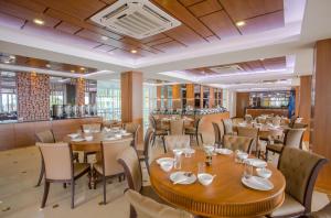 a restaurant with tables and chairs and a bar at Saint Tropez Beach Hotel in Chao Lao Beach