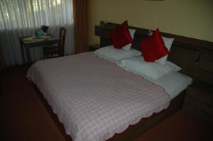 a bedroom with a large bed with red pillows at Gasthof Holländer Eck in Lennestadt