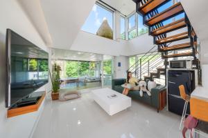 a woman sitting on a couch in a living room at Gapyeong Bobo Dog Pool Villa in Gapyeong