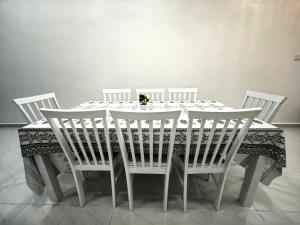 a dining room table with four white chairs and a table cloth at Tanjong Suite Homestay in Kampong Tok Pakir