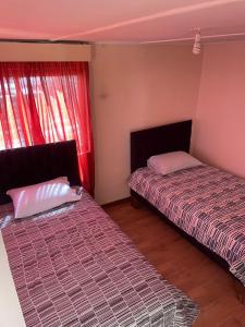 two beds in a room with red curtains at Casa amoblada para 8 personas in Calama