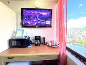 a television on a wall above a desk with a microwave at Waikiki Canal Family Room 6person in Honolulu