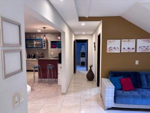 a living room with a blue couch and a kitchen at Residência Naiote in Japaratinga