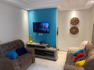 a living room with two couches and a flat screen tv at Residência Naiote in Japaratinga