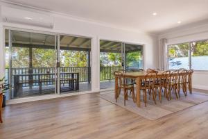 a dining room with a table and chairs and windows at Billie's on Smiths in Smiths Lake