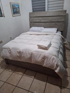 Humacao Guest House 4 في هوماكاو: سرير عليه ملاءات ووسائد بيضاء