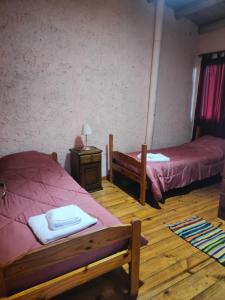 a bedroom with two beds and a table with a lamp at Cabañas El Rosedal in San Rafael