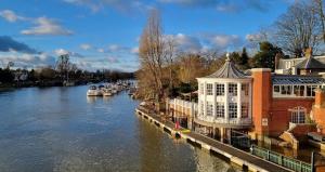 a view of a river with buildings and boats at Loft Flat, near Hampton Court Palace, Free Parking in West Molesey