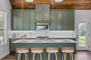 a kitchen with green cabinets and bar stools at The June Hot tub with king beds on 2 acres in Hot Springs