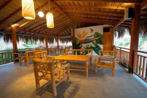 a restaurant with wooden tables and chairs and a painting at Panorama garden inn in Máncora