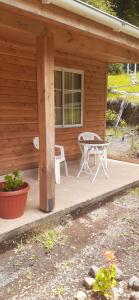 a porch of a cabin with a table and chairs at Hostal Conaripe Alto sector Termas in Coñaripe +9 photos