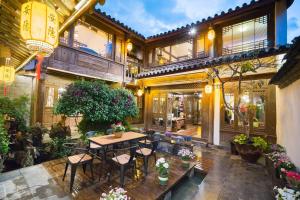 麗江市にあるBig Tree Guesthouse - Naxi old styleのテーブルと椅子のあるパティオのある家