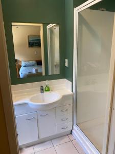 a bathroom with a sink and a shower with a mirror at Beach Break in Mount Maunganui