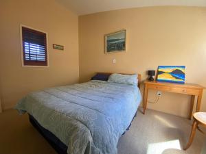 a bedroom with a bed and a wooden table at Beach Break in Mount Maunganui