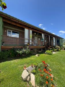 a house with a yard with flowers in front of it at Abrazados Suites del Valle in Villa Yacanto
