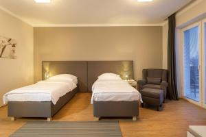 a hotel room with two beds and a chair at Apartmány Abacie in Nový Jičín