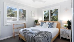 ein Schlafzimmer mit einem Bett und zwei Fenstern in der Unterkunft Coastal Palms in Culburra Beach