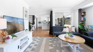 ein Wohnzimmer mit Fernseher und Sofa in der Unterkunft Coastal Palms in Culburra Beach