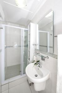 a white bathroom with a sink and a shower at Kingfisher GuestHouse in Port Elizabeth +92 photos