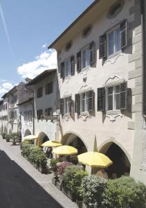 un edificio con sombrillas amarillas delante de él en Hotel Andreas Hofer, en Egna
