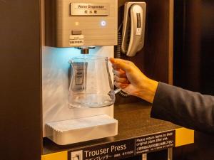 a person is pressing a transfer press into an atm machine at APA Hotel & Resort Osaka Namba Ekimae Tower in Osaka
