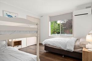 卡尔斯The Green Garden Gate - Phillip Island的一间卧室，有两张双层床和一扇窗户