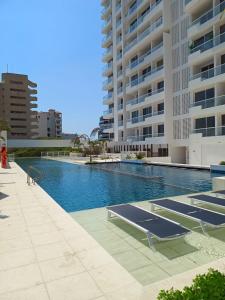 a swimming pool with blue water in front of a building at Santa Marta - Porto Horizonte in Santa Marta