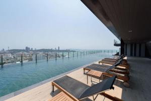 una fila di chaise longue e sedie su un edificio con vista sull'acqua di The Base - Spacious 70sqm, 2 Bedroom, 2 bathroom, Penthouse Condo - Pattaya City Centre - 592 a Centro di Pattaya