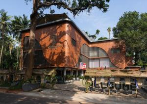 CalicutSanketam Motel的一栋前面有棵树的建筑物