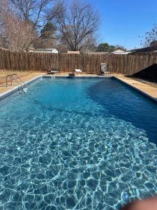 a swimming pool with blue water and a wooden fence at Sweet Home Alabama 4BR 2BA oasis with pool WI-FI in Montgomery