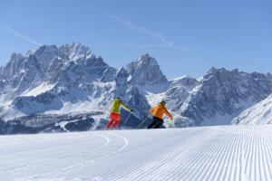 two people are skiing down a snow covered mountain at Appartements Schäfer in San Candido